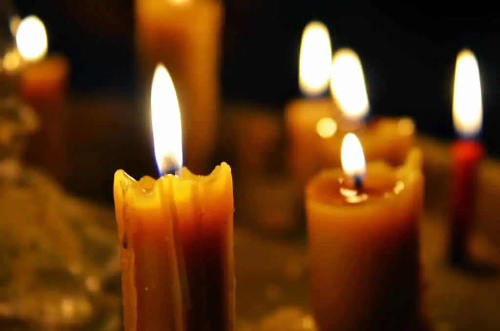 A warm, tranquil ambiance created by a group of burning candles with glowing flames, casting a soft light in a dark setting.